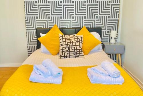um quarto com uma cama amarela com toalhas em Cosy Haven Wembley em Wembley