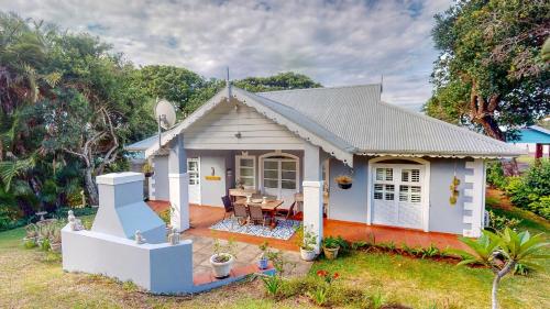 Casa blanca pequeña con mesa y sillas en Rose Cottage in Caribbean Estate, en Port Edward