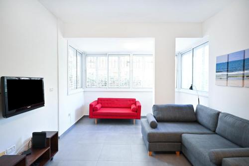 een woonkamer met een rode bank en een tv bij Winds of Change by HolyGuest in Tel Aviv