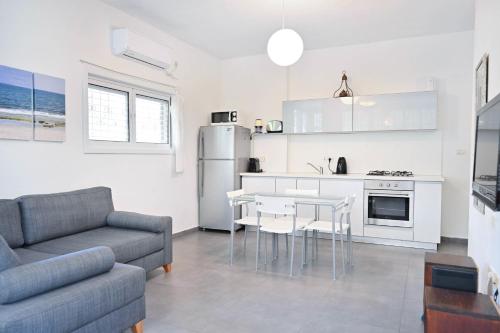 een keuken en een woonkamer met een bank en een tafel bij Winds of Change by HolyGuest in Tel Aviv