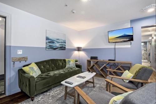 a living room with a green couch and a tv at The Wesley Walla Walla in Walla Walla