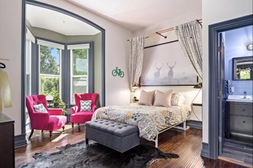 a bedroom with a bed and two pink chairs at The Wesley Walla Walla in Walla Walla