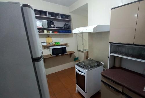 una pequeña cocina con nevera y microondas en Apartamento Di Cavalcanti, en Guarapari