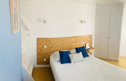 sypialnia z białym łóżkiem z niebieskimi poduszkami w obiekcie Résidence Thibaud w Tuluzie