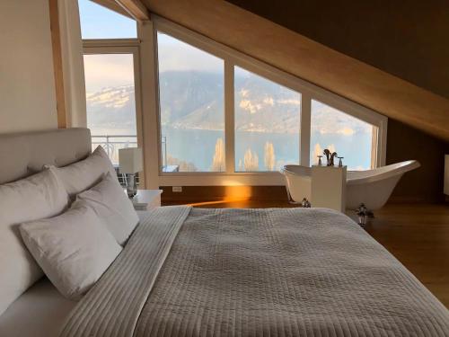 1 dormitorio con 1 cama grande y bañera en Lakeview Gem en Krattigen