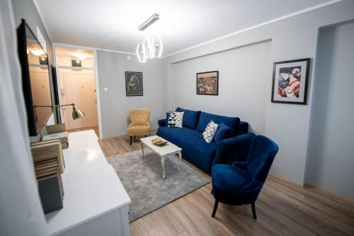 uma sala de estar com um sofá azul e uma cadeira em K Milutina em Belgrado