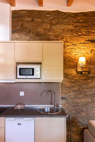 a kitchen with a sink and a microwave at Casas de Campo do Castro da Cola in Marchicão