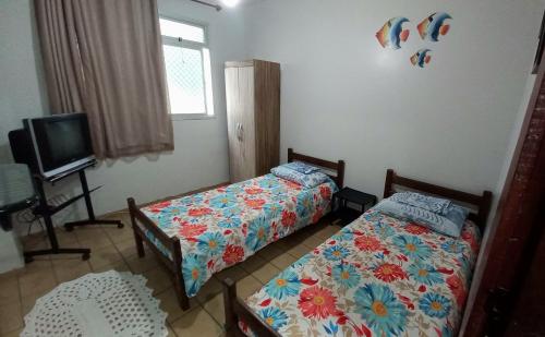 1 dormitorio con 2 camas y TV. en Apartamento Di Cavalcanti, en Guarapari