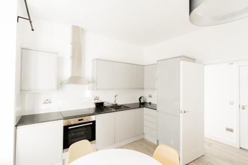 a white kitchen with white cabinets and a table at The Apartments Kensington High Street in London