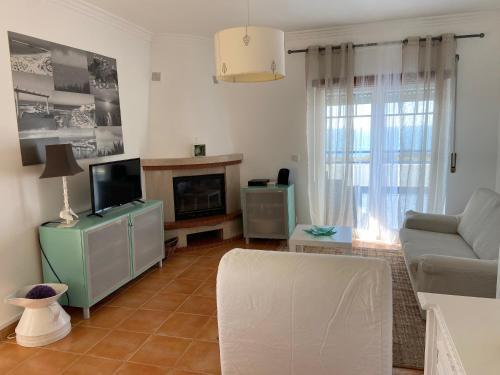 a living room with a couch and a tv at Ericeira Ocean View Apartment in Ericeira