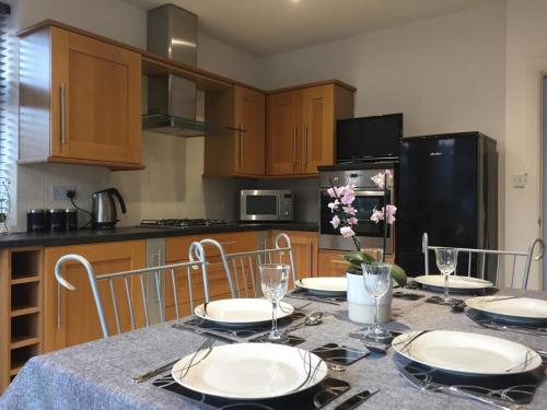 a kitchen with a table with plates and flowers on it at Cederee in Rhyl