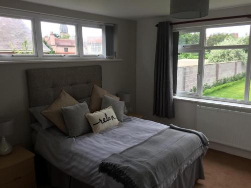 a bedroom with a bed with pillows and two windows at Cederee in Rhyl