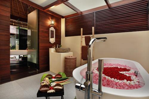 a bathroom with a bath tub filled with red flowers at Bali Nusa Dua Hotel in Nusa Dua