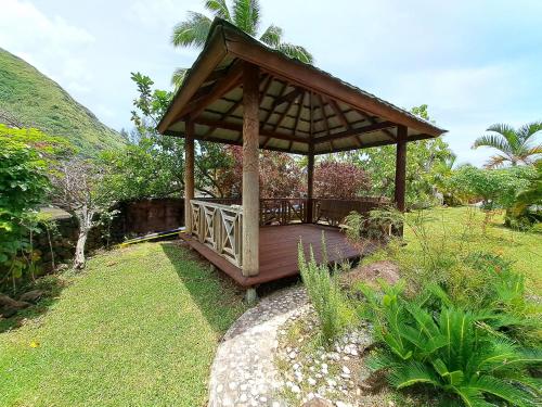 a wooden gazebo in the middle of a garden at MOOREA - Bungalow Moekea Lagoon in Hauru