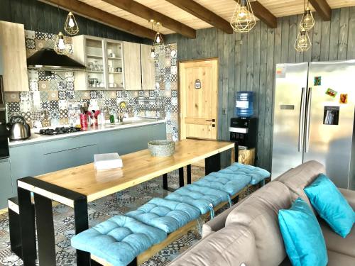 a kitchen with a table and a couch and a refrigerator at Maravillosas Vistas Boyeruca Lodge in Vichuquén
