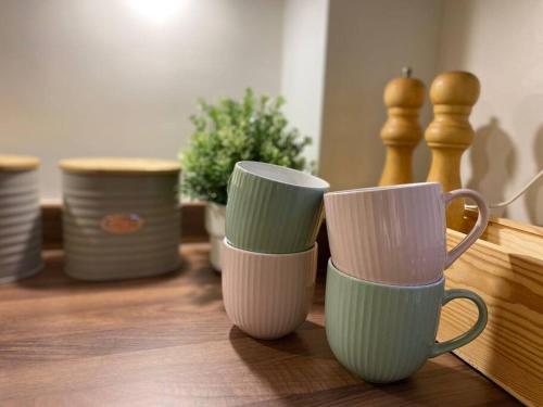 three cups sitting on top of a wooden table at Stylish Apartment in Leafy Ealing in Ealing