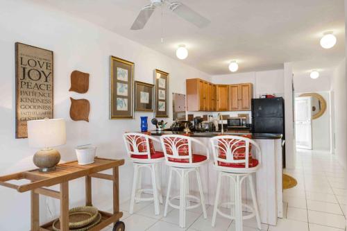 a kitchen with red and white stools and a counter at Turtle's Nest Beach Resort in Meads Bay