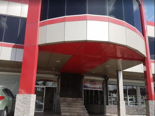 a red white and blue building with a car parked outside at 2br Apt in St Helena - 6mins from the airport Perfect for short and long stays in Piarco