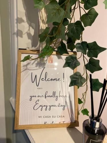 a sign in a wooden frame next to a plant at Stylish Apartment in Leafy Ealing in Ealing