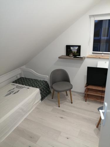 a bedroom with a bed and a chair and a television at Ferienhaus Brise Ostsee in Kalkhorst