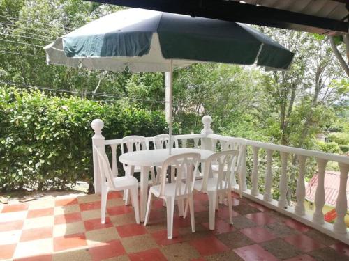 una mesa, sillas y una sombrilla en el porche en Casa en Condominio Campestre en Tocaima, en Jerusalén