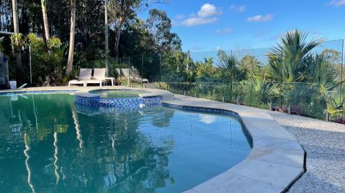 uma piscina num quintal com duas cadeiras em Como Guest Suite em Gold Coast