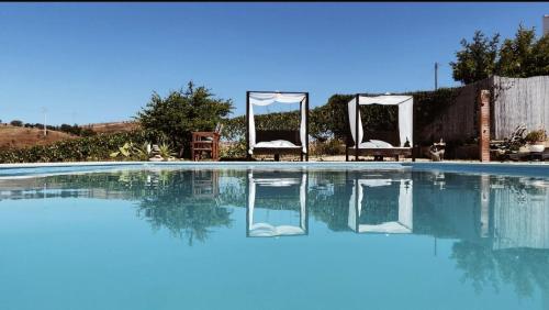 an empty swimming pool with two chairs and a wedding marquee at Casas de Campo do Castro da Cola in Marchicão