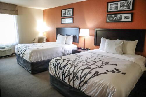 two beds in a hotel room with orange walls at Sleep Inn & Suites Ocala - Belleview in Marion Oaks