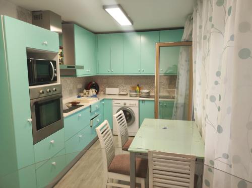 una cucina con armadi blu, tavolo e sedie di Apartamento playa de Chancelas, Pontevedra a Combarro