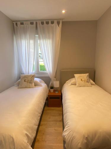 2 camas en una habitación con ventana en Apartamento Lumokobide, en Guernica y Luno