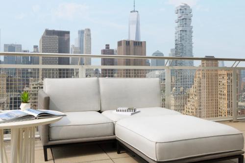a white couch sitting on a balcony with a city skyline at NoMo SoHo in New York