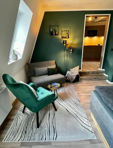 a living room with a green chair and a couch at HEIMATliebe Apartment für 2 in Blankenhain