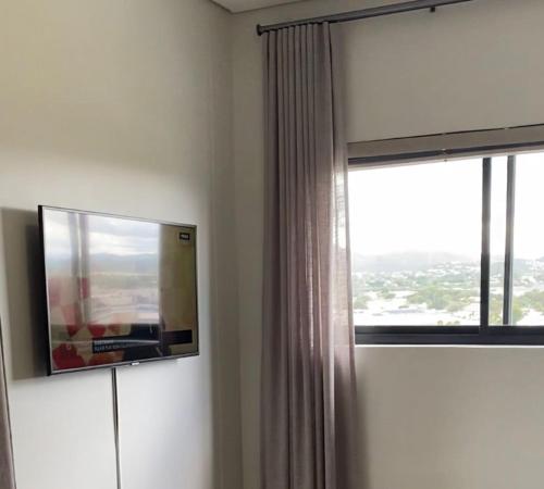 a living room with a tv and a window at DMN City at Merensky Apartment in Windhoek