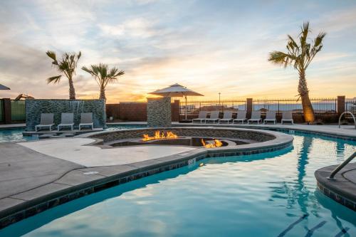 a swimming pool with a fire pit and palm trees at Zion Village Oasis by the Pool with Lazy River in Hurricane