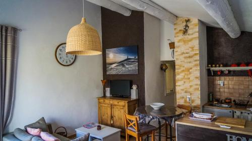 sala de estar con mesa y reloj en la pared en La belle histoire Gîte Ventoux, en Bédoin