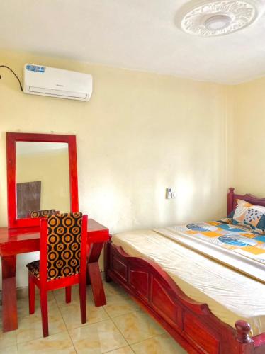 a bedroom with a bed and a chair and a mirror at APEX ANNEX Guest Facility in Buea