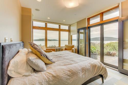 a bedroom with a large bed with windows at Fidalgo Island Waterfront Stunner in Anacortes