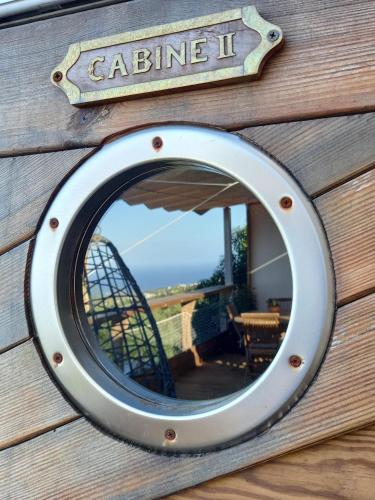a circular mirror on the side of a wooden wall at Le Noé in Saint-Leu