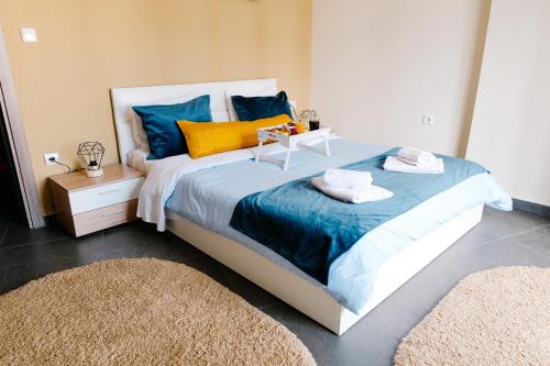 - une chambre dotée d'un grand lit avec des oreillers bleus et jaunes dans l'établissement Violet City Center Apartments, à Kavala