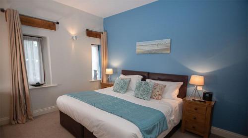 a blue bedroom with a large bed with pillows at Watson Cottage, Castle Carrock, Nr Carlisle in Castle Carrock