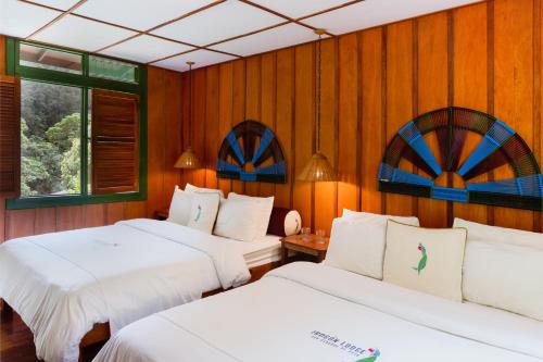 two beds in a room with wooden walls at Trogon Lodge in San Gerardo de Dota