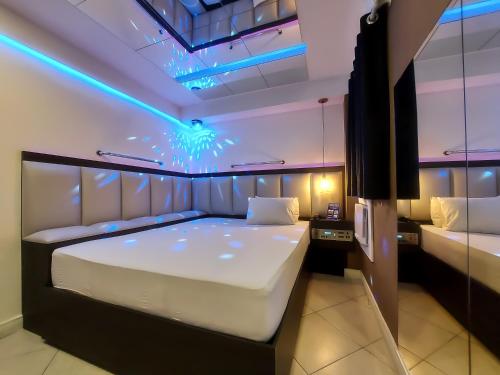 1 dormitorio con 1 cama grande con luces azules en Motel Messalina en São Paulo