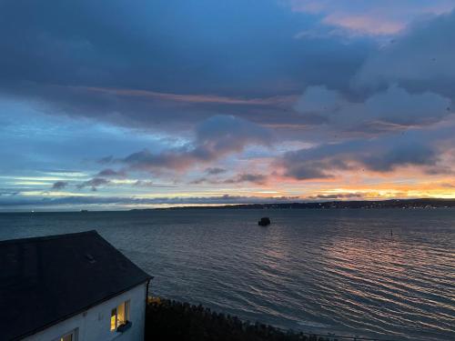 a sunset over a large body of water at For Sea Lovers ! Coastguard Boat House right on Belfast Lough in Newtownabbey