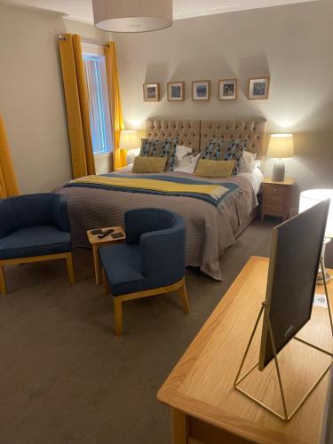 een slaapkamer met een bed en 2 stoelen en een bureau bij Horncliffe room only accommodation in Seahouses