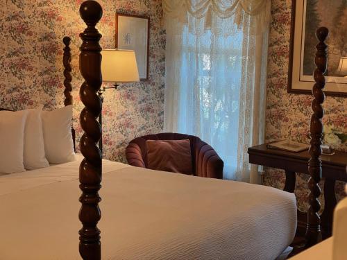 a bedroom with a bed and a chair next to a window at Central House Inn in Bar Harbor