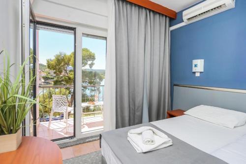 a hotel room with a bed and a balcony at Hotel Lumbarda in Lumbarda