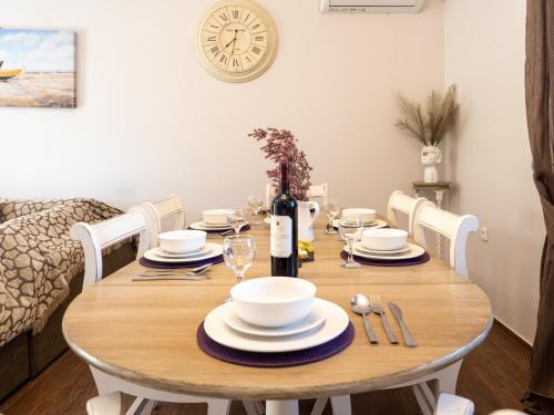a dining room table with white dishes and a bottle of wine at Euphoria Country House in Agios Ioannis