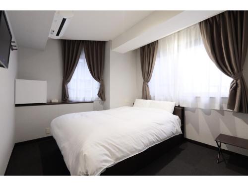 草津的住宿－Kusatsu Onsen 326 Yamanoyu Hotel - Vacation STAY 10349v，卧室配有白色的床和2扇窗户。