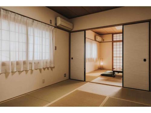 ein leeres Zimmer mit einer Tür und einem Fenster in der Unterkunft MEILAN HOUSE - Vacation STAY 13804 in Osaka