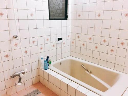 eine Badewanne im Bad mit weißen Fliesen in der Unterkunft MEILAN HOUSE - Vacation STAY 13804 in Osaka